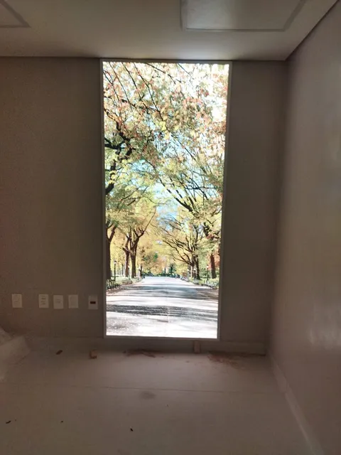 Painel retroiluminado simulando janela com vista de parque em sala fechada
