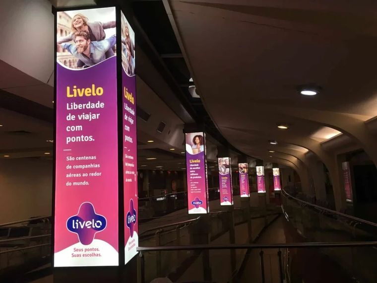 Totens iluminados da campanha Livelo instalados em colunas de aeroporto